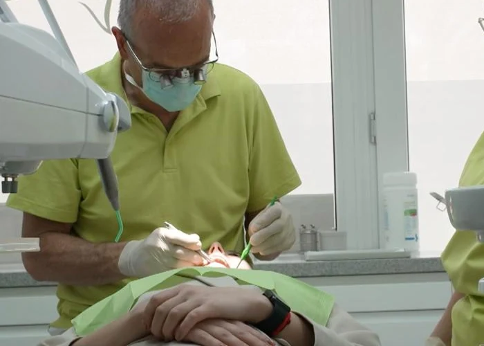 Drs. Hans van der Elst bei der Behandlung, konzentriert über die Patientin gebeugt